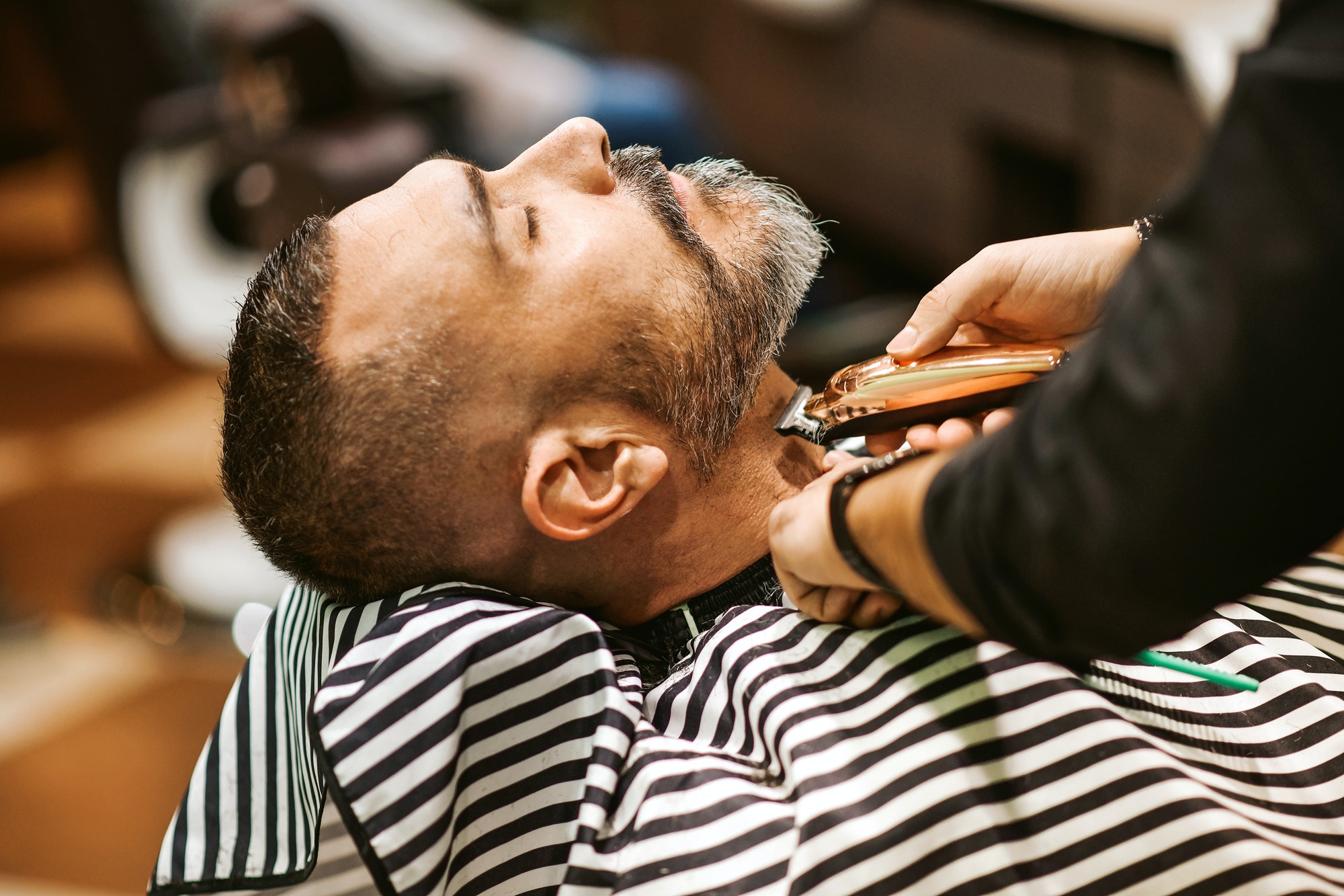 Barber trims the beard of the customer